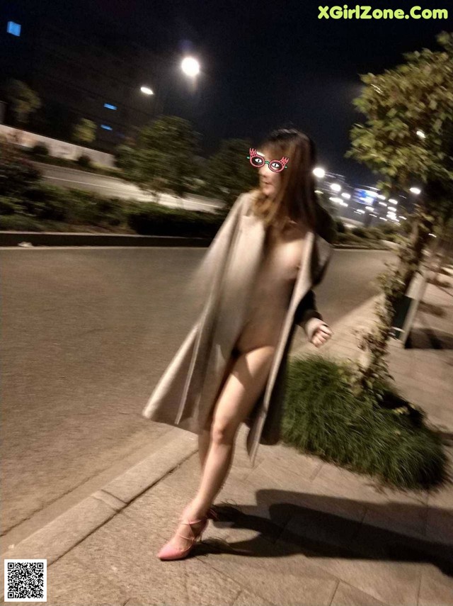 A woman walking down a street at night. 