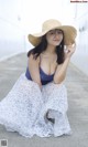 A woman wearing a straw hat sitting on the ground.