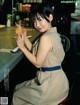 A woman sitting at a bar holding a glass of orange juice.