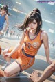 A woman in an orange basketball uniform crouching on a basketball court.