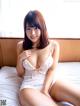 A woman in a white lingerie sitting on a bed.