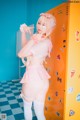 A woman in a pink and white outfit posing in front of lockers.