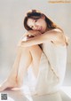 A woman in a white dress sitting on a white surface.