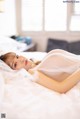 A woman laying on a bed in a white dress.