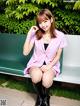 A woman in a pink shirt and black boots sitting on a bench.