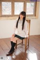 A woman sitting on a wooden chair in a room.